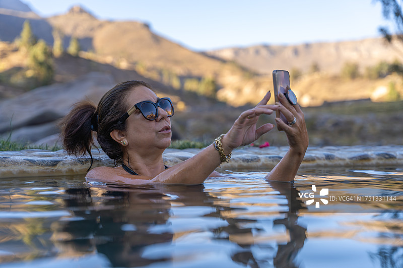 女人在山间温泉中使用手机图片素材