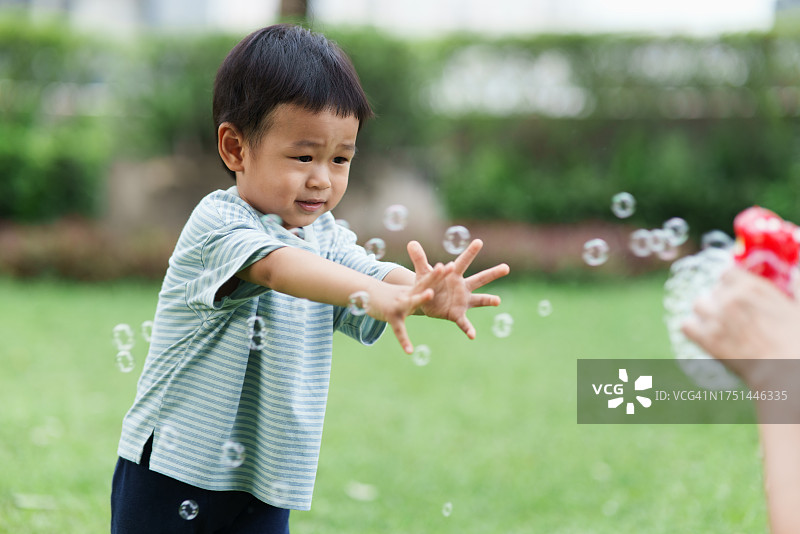 可爱的亚洲儿童和母亲在户外城市花园玩肥皂泡图片素材