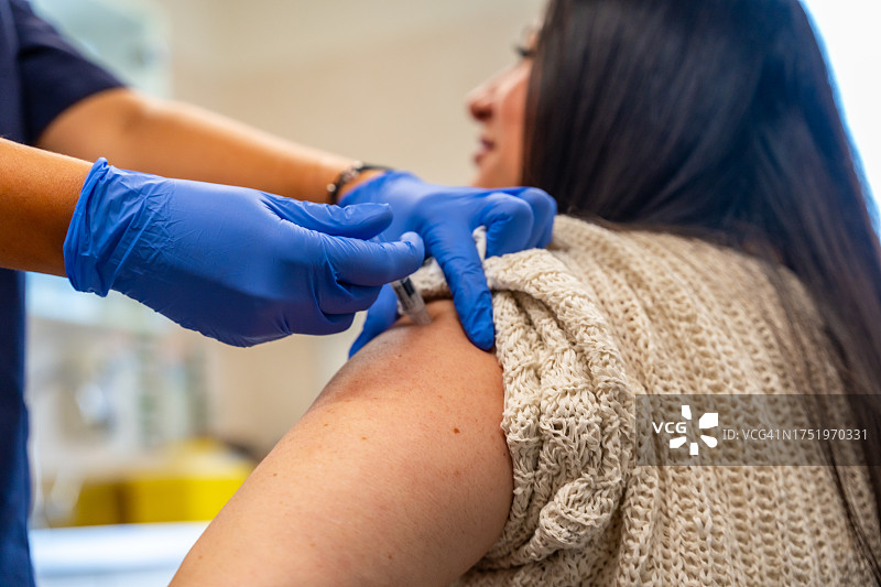 医疗中心护士为冬季流感疫苗接种活动注射疫苗的手部细节图片素材