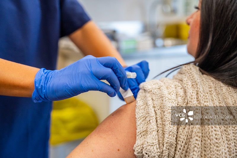 一位不知名的护士在医疗中心注射流感疫苗，以对抗冬季疾病图片素材