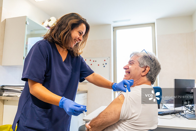微笑的护士在医疗中心为老年患者注射流感疫苗，以对抗冬季疾病或感染图片素材