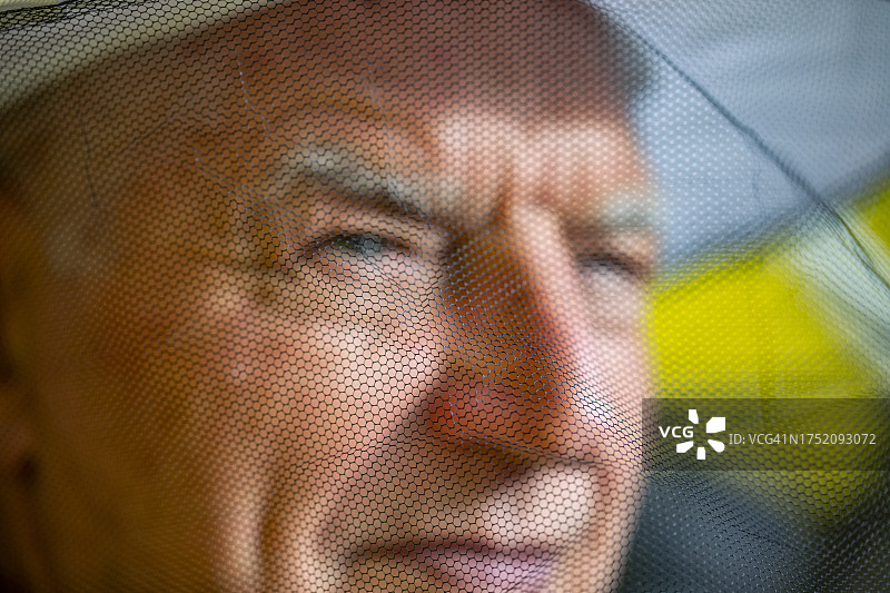 戴防护网帽子的微笑老年养蜂人特写图片素材