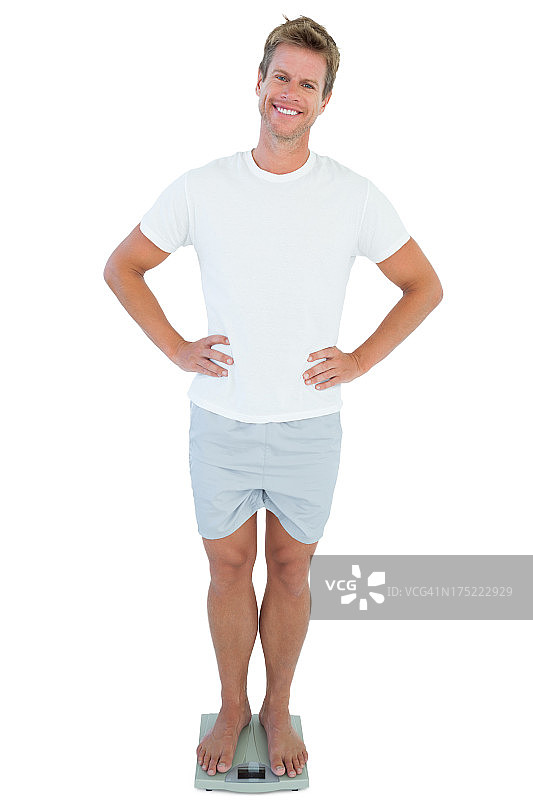 快乐的男人站在体重秤上图片素材