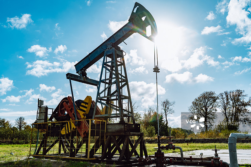 天然气和石油勘探开采：抽油机在深蓝色天空下的油田工作图片素材