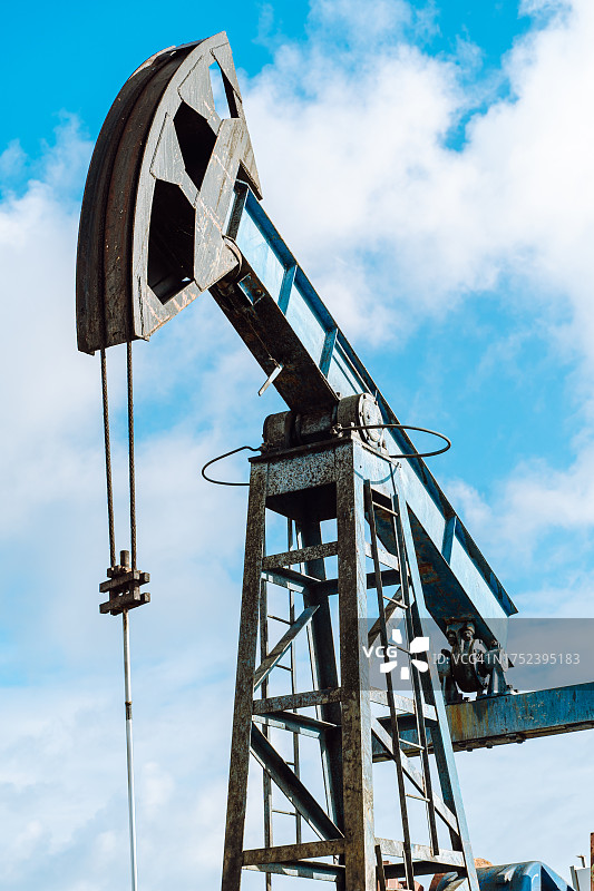 蓝色天空下的蓝色抽油机。低角度图片素材