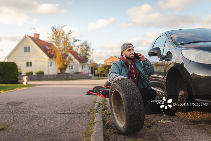 年轻人在户外换轮胎寻求帮助图片素材