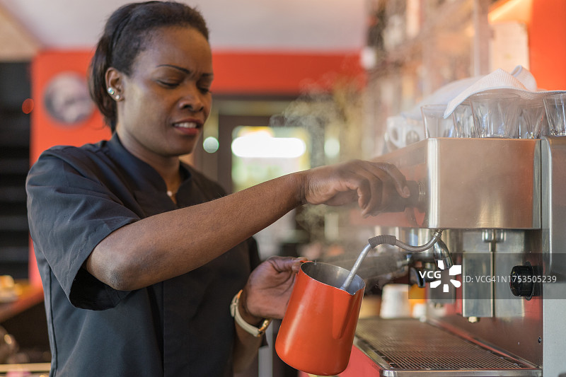 咖啡师在咖啡店用机器制作牛奶图片素材