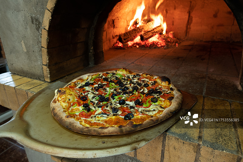 在家烹饪意大利披萨：传统烤箱和燃烧的木柴图片素材