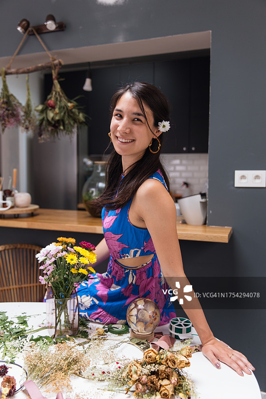 在家中，被鲜花和工艺品材料包围的日裔女子图片素材