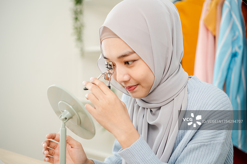 戴着头巾的年轻穆斯林女性用睫毛夹化妆特写图片素材