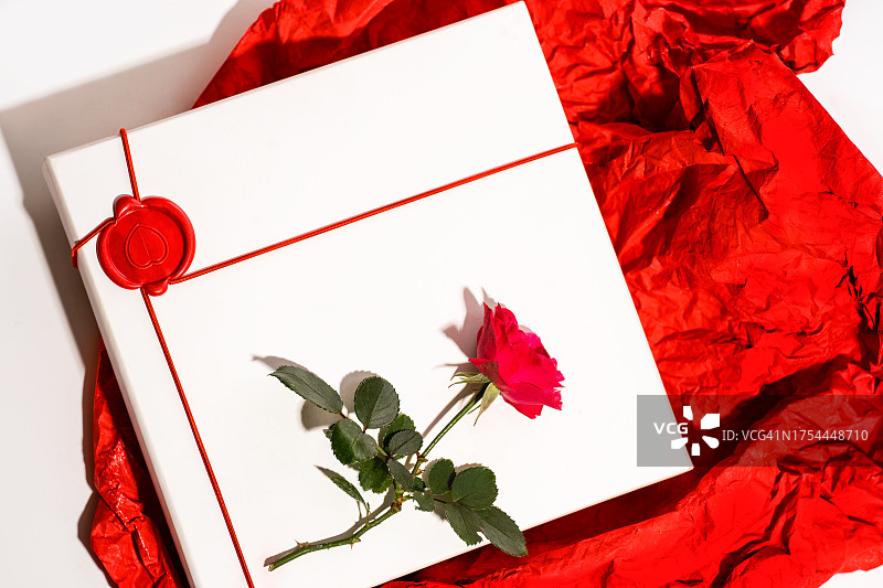 情人节和妇女节贺卡，红玫瑰，白色礼盒，白色背景的红色包装纸。图片素材