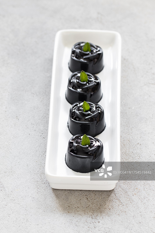 迷你玫瑰造型的抹茶奶油蛋糕。配酱汁，浅灰色背景，特写图片素材