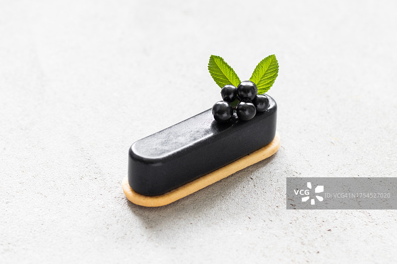 饼干上的黑色抹茶奶油甜点。用黑色浆果装饰。浅灰色背景。特写图片素材