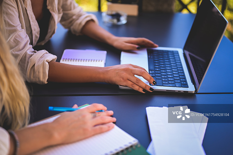 两位女商人户外使用笔记本电脑工作，手部特写图片素材