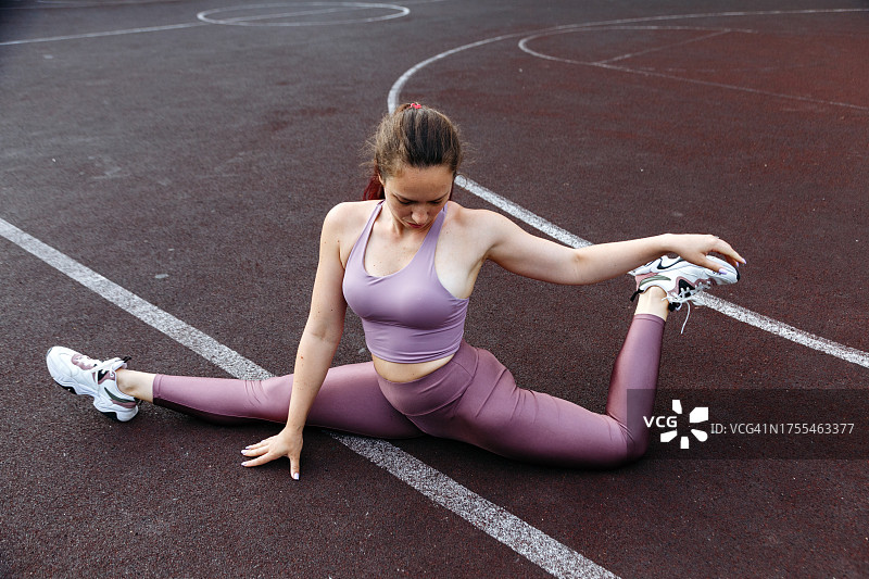 身穿健身服的运动女孩在操场上训练，年轻女子正在做伸展运动图片素材
