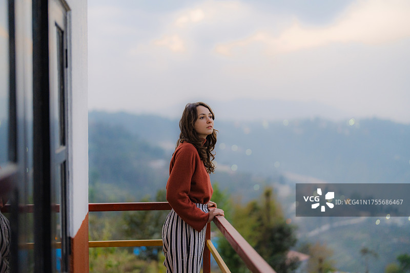 女人坐在酒店阳台上看山图片素材