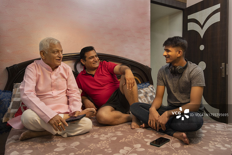 印度多代家庭坐在卧室的床上图片素材