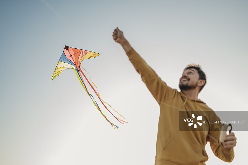 快乐的男人在天空下放风筝图片素材