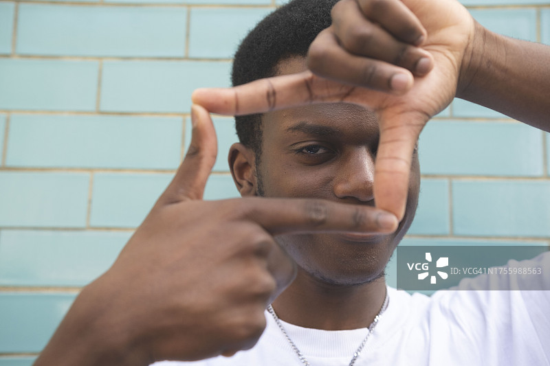 年轻男子在墙前用手指比框架图片素材