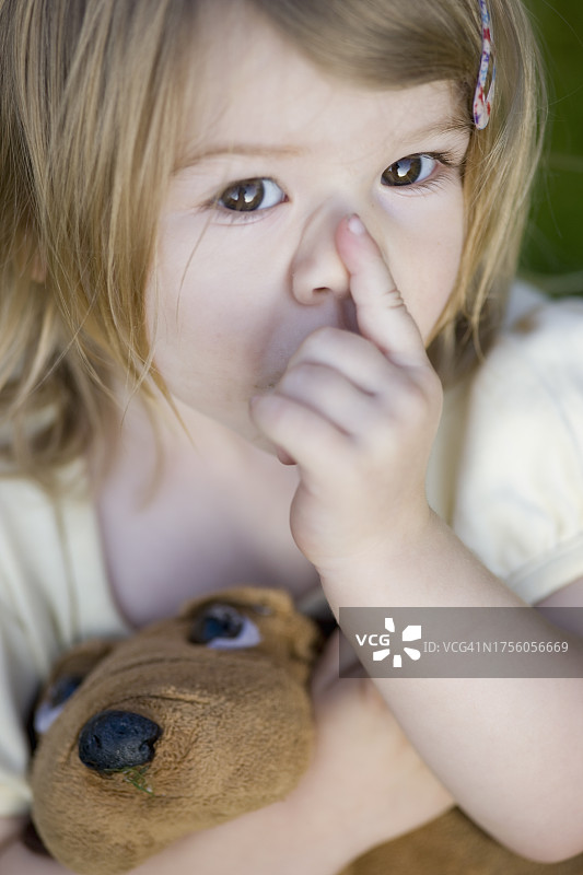 吮吸手指并抱着毛绒玩具的女孩图片素材