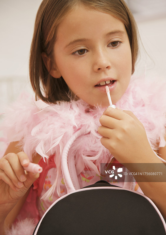 戴着粉色羽毛围巾，涂唇彩的女孩图片素材