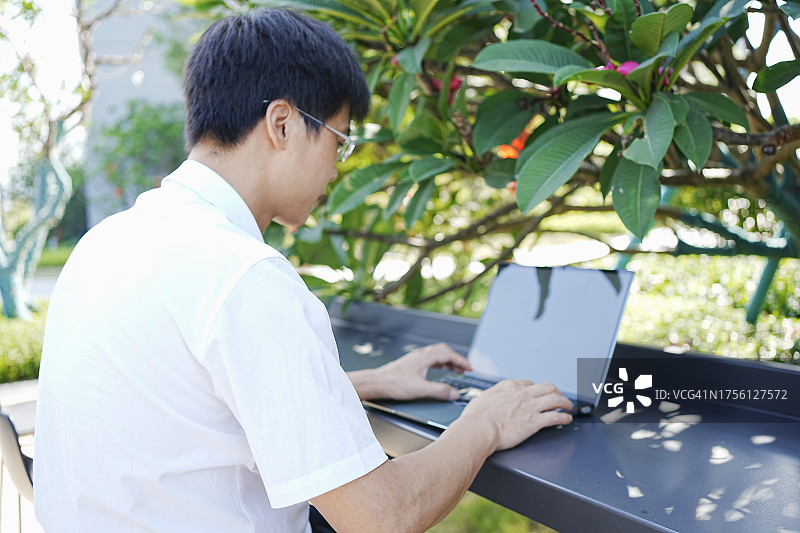 在户外公园用笔记本电脑远程办公，以自然风光为背景图片素材