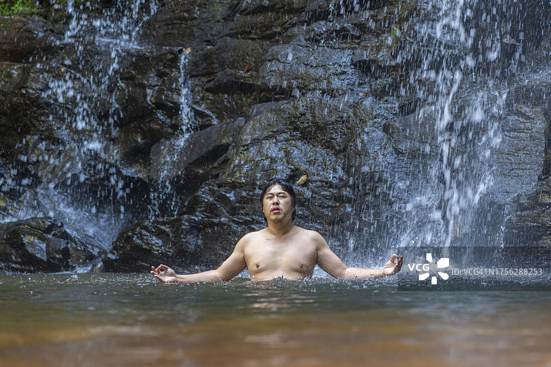 男人在瀑布下放松图片素材