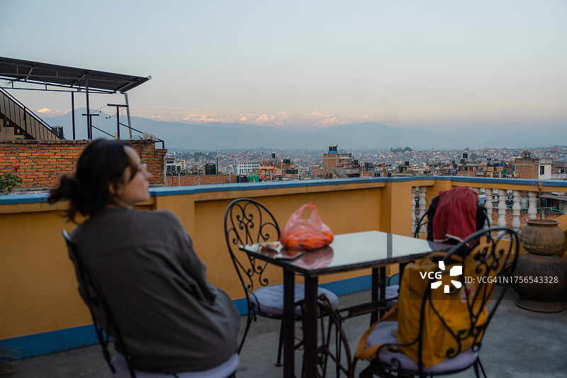女人坐在露台上欣赏喜马拉雅山的景色图片素材