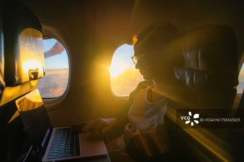 女人在飞机上使用笔记本电脑工作图片素材
