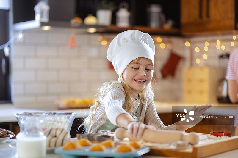 戴着厨师帽在厨房里的小女孩图片素材