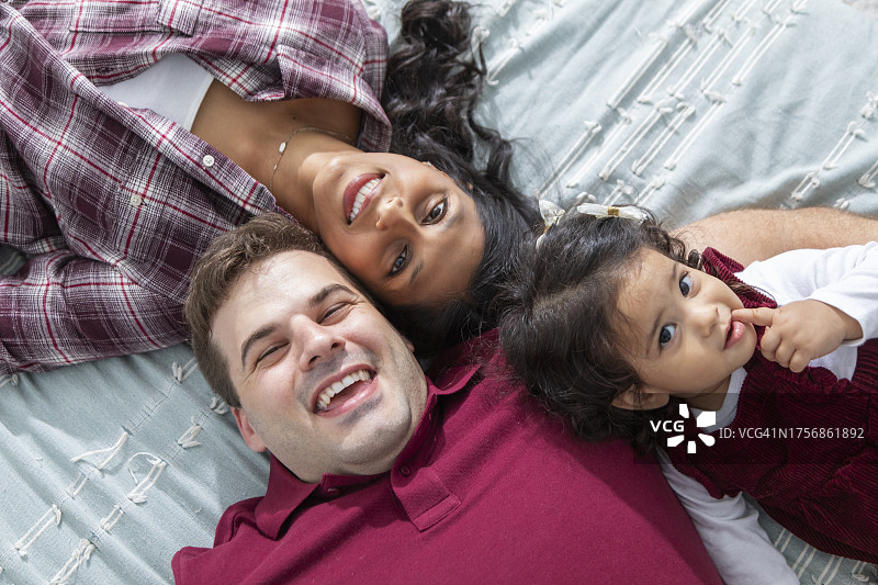 和女儿一起躺在床上的年轻情侣图片素材