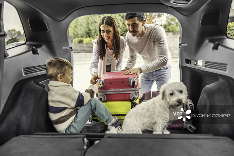 幸福的三口之家带着爱犬，将行李装上车准备旅行图片素材