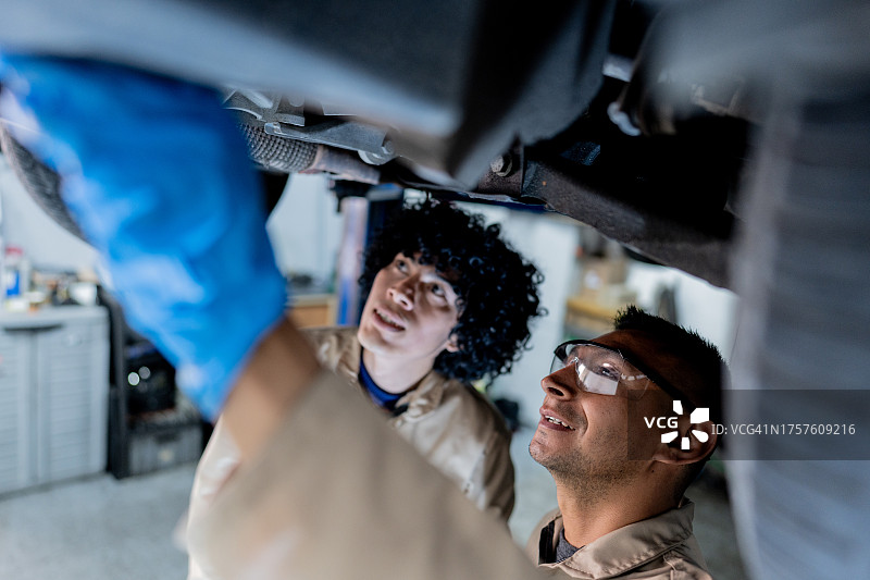 汽车修理工在修理店教他的助手图片素材