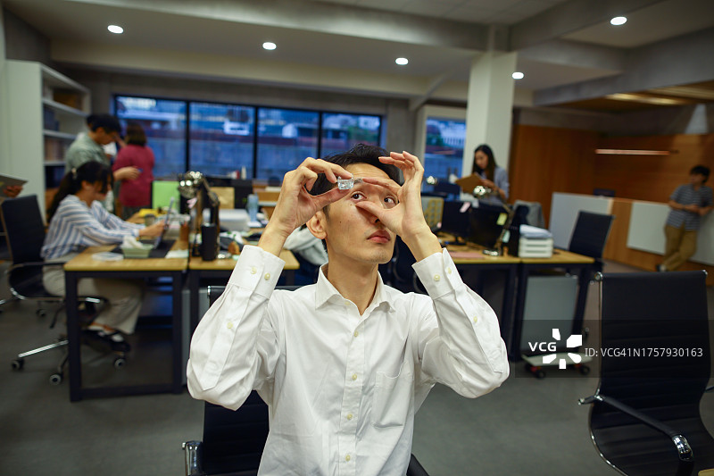 长时间工作后眼睛不适，准备滴眼药水的亚洲男人图片素材