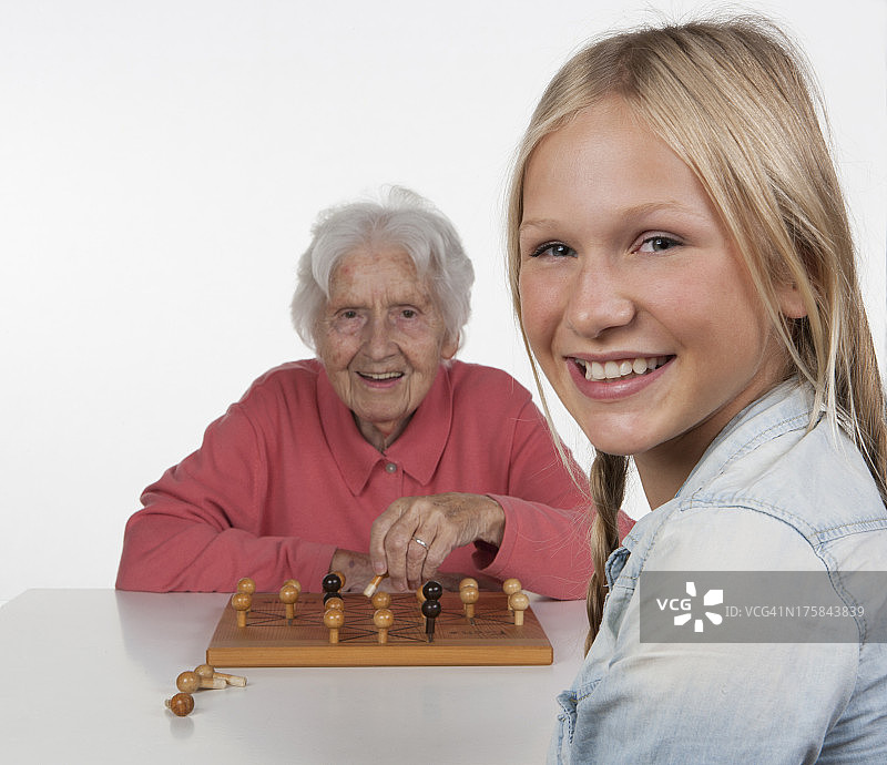 老年女性和少女玩狐狸与母鸡游戏，微笑图片素材