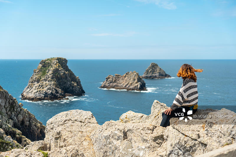 在法国布列塔尼克罗宗半岛的彭伊尔角，年轻女游客看着大海，三个著名小岛，法国图片素材