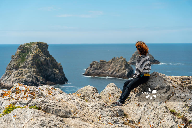 在法国布列塔尼克罗宗半岛的彭伊尔角，年轻女游客看着大海，三个著名小岛，法国图片素材