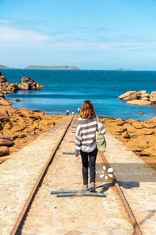 在法国布列塔尼省的佩罗斯-古雷镇，一名年轻女子在普劳马纳赫港的米恩鲁兹灯塔旁乘船下船图片素材