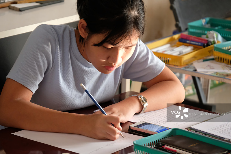 年轻的亚洲女学生在家做作业，教育理念图片素材