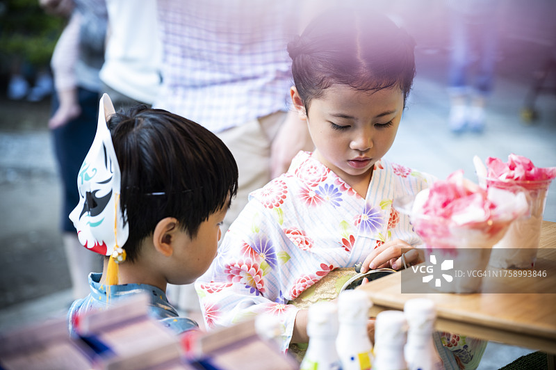 穿着浴衣在祭典小吃摊玩耍的儿童图片素材