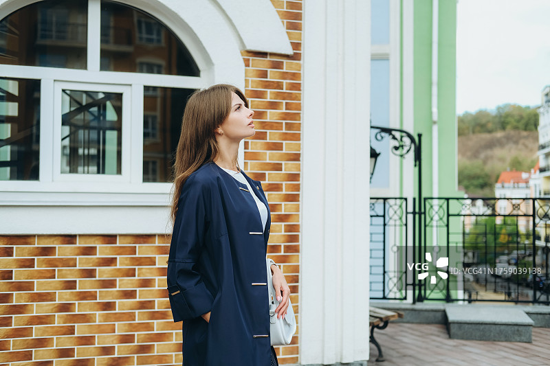 在拱形窗边，抬头看着的深蓝色外套年轻女人图片素材