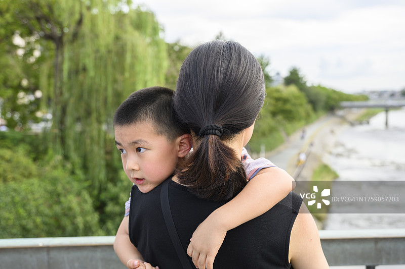 一位亚洲女性抱着疲惫的孩子图片素材