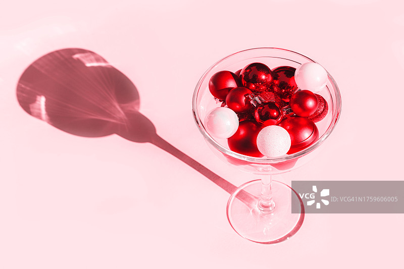 圣诞节装饰品——粉红色背景下，鸡尾酒杯中的红白球，带阴影图片素材