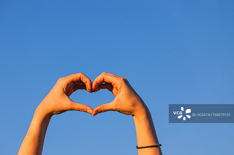 女子在蓝天前用手比心（美国加利福尼亚州都柏林）图片素材