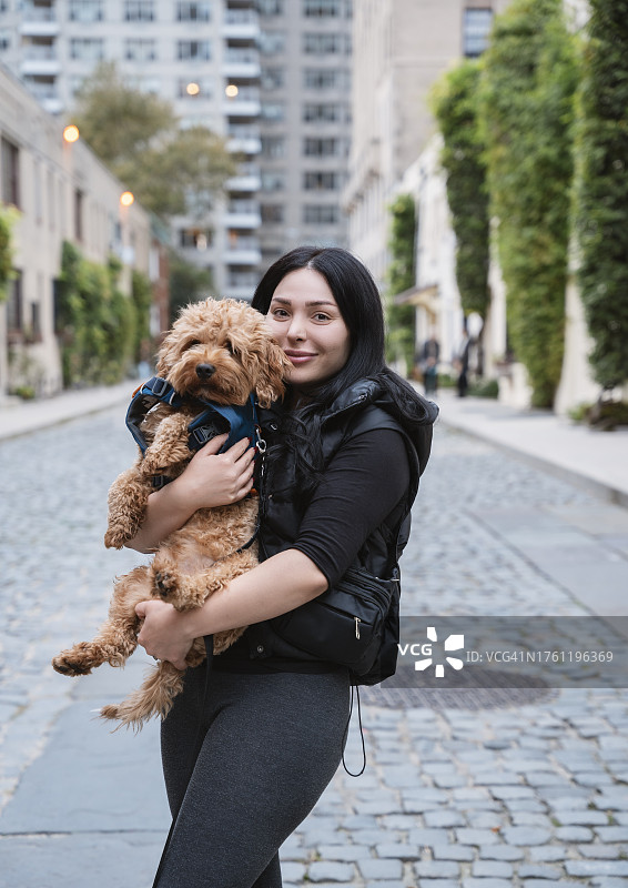 年轻女子和她的玩具贵宾犬在纽约曼哈顿街头图片素材