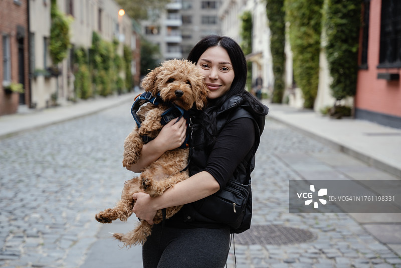 年轻女子和她的玩具贵宾犬在纽约曼哈顿街头图片素材