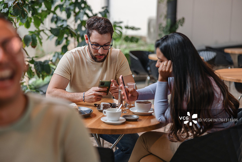 在咖啡店使用智能手机而不是交谈的年轻夫妇图片素材