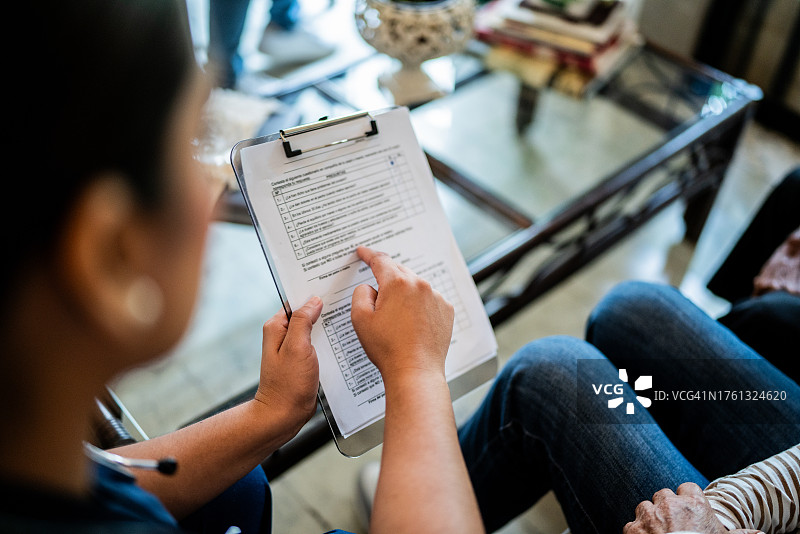 居家护理员向患者展示病历图片素材