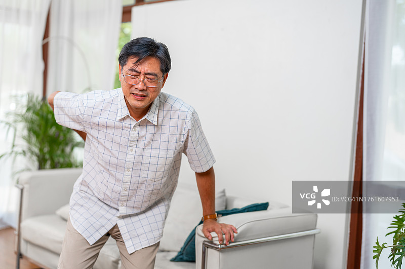 站在客厅里的背痛老年男人图片素材