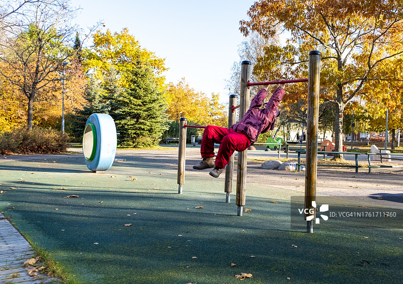 秋季游乐场8岁白人女孩玩单杠图片素材